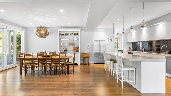 Timber floors, a large dining area and kitchen with an island bench inside the home.