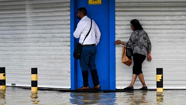 People try to avoid getting wet as they cross a flooded street following heavy rains in Sharjah. Picture: Ahmed Ramazan / AFP