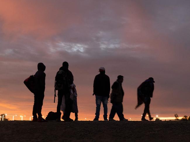 (FILES) Parents-to-be from Haiti stand at a gap in the US-Mexico border wall after having travelled from South America to the United States, in Yuma, Arizona, on December 10, 2021. The massive emigration of Cubans and Haitians to the United States via Nicaragua triggered the transit of sub-chartered flights, with special routes and stratospheric prices, prompting sanctions from Washington amid a recent spike in the flow of migrants. According to an Inter-American Dialogue report, a monthly average of 50 charter flights travelled from Havana to Managua between January and October 2023, while from Port-au-Prince these operations rose from 30 in August to 100 in September and 130 in October. (Photo by JOHN MOORE / GETTY IMAGES NORTH AMERICA / AFP)