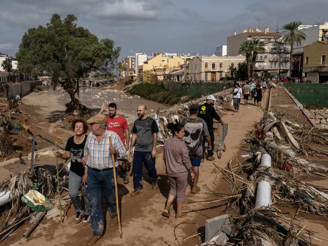 People cross a bridge through piles of debris after floods hit parts of the country in the Paiporta municipality of Valencia, Spain. Picture: Getty Images