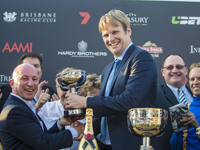 Trainer Bjorn Baker receives his trophy from former jockey Jimmy Cassidy after Music Magnate won the Doomben 10,000. Picture: AAP