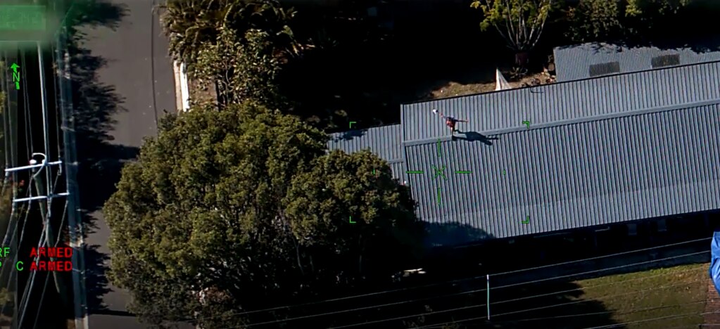 One of the men climbed on the roof in an attempt to evade officers. He is pictured surrendering.