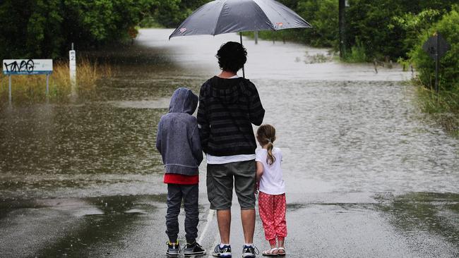 Local resident Shane Hawkins and his kids Jasper and Lilah check out the severe flooding on Burns Road in Ourimbah.