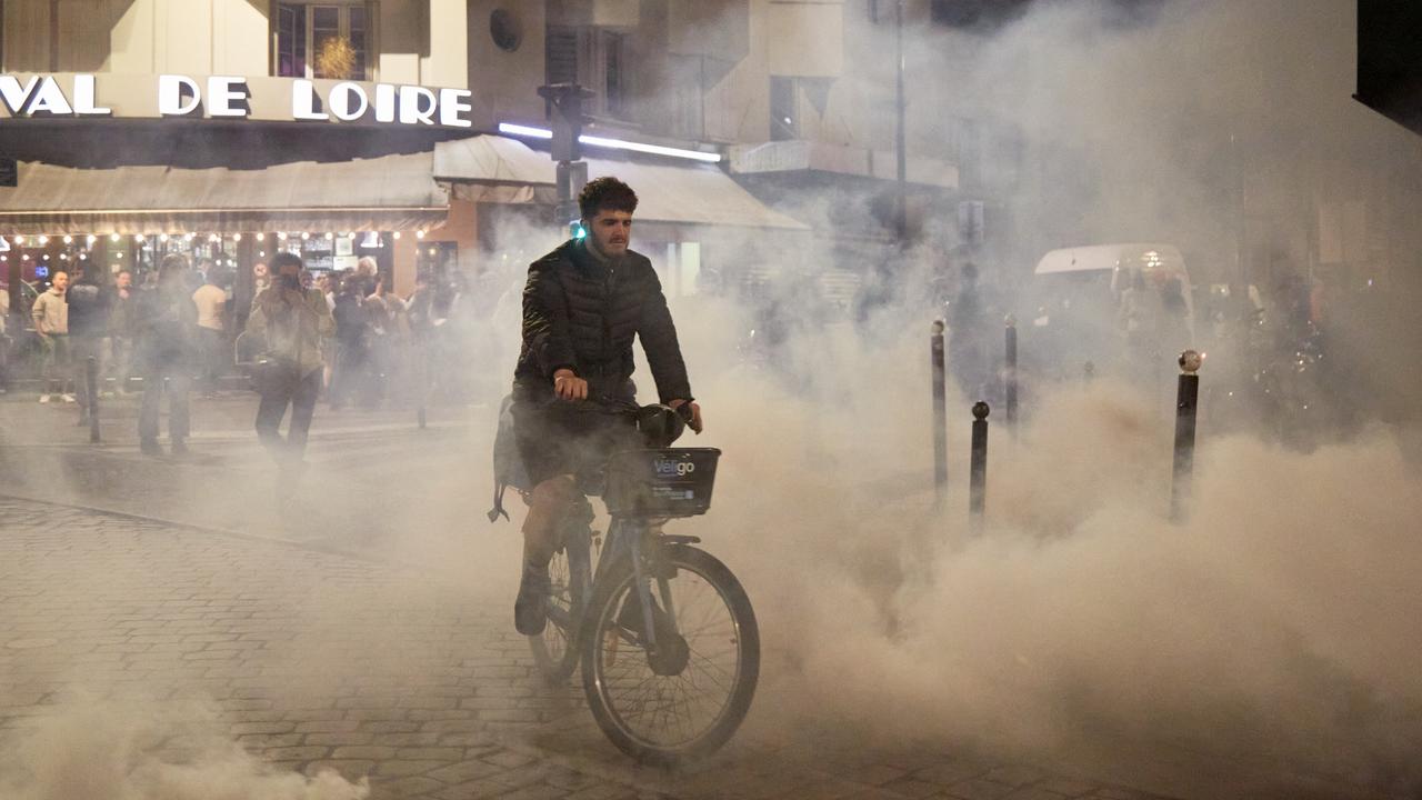 A man cycles through clouds of tear gas fired by anti-riot police officers in Paris. Picture: Pierre Crom/Getty Images