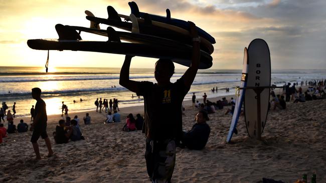 Amid the tourists and rubbish on Kuta beach, you’ll find so called ‘beach boys’, catering to the needs of female visitors. Picture: AFP Photo / Sonny Tumbelaka