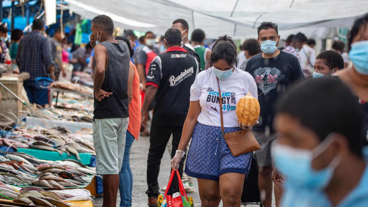 Residents in Suva, Fiji, wear masks as they walk through the fish market. Picture: Leon Lord/ AFP