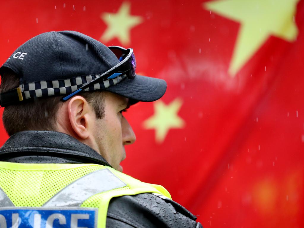 A police officer stands in front of a Chinese flag during a pro-democracy Hong Kong rally at Rundle Mall in Adelaide, Sunday, August 18, 2019. (AAP Image/Kelly Barnes) NO ARCHIVING