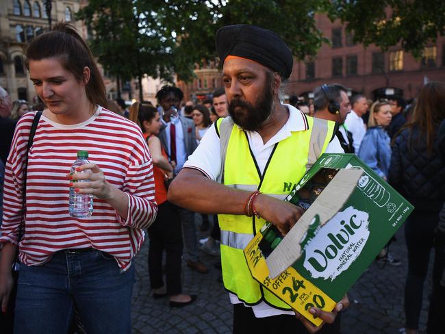 A man hands out free bottles of water as members of the public gather at a vigil, to honour the victims of Monday evening's terror attack, at Albert Square.  Picture:  Getty