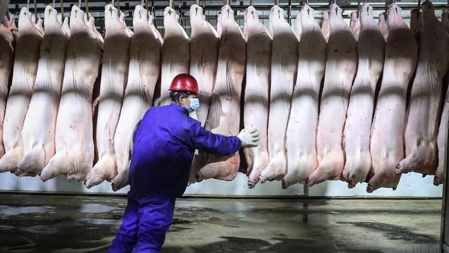 An employee works on a pork production line at a food factory in Shenyang, in northeastern China's Shenyang province. Picture: STR / AFP