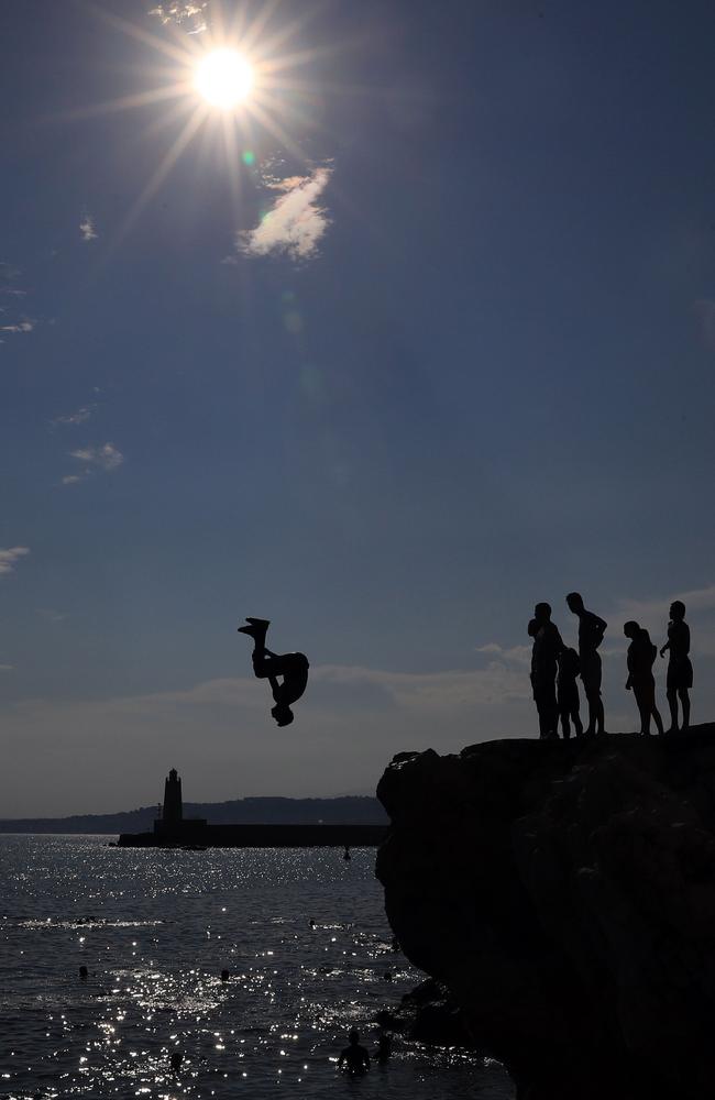 Young men leap off rocks into the ocean at Nice, southeastern France. Picture: Valery Hache