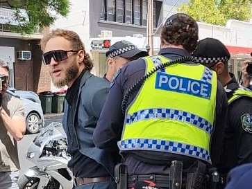 Joel Davis arrested by SAPOL officers for displaying nazi symbol at rally yesterday. Picture: The Advertiser