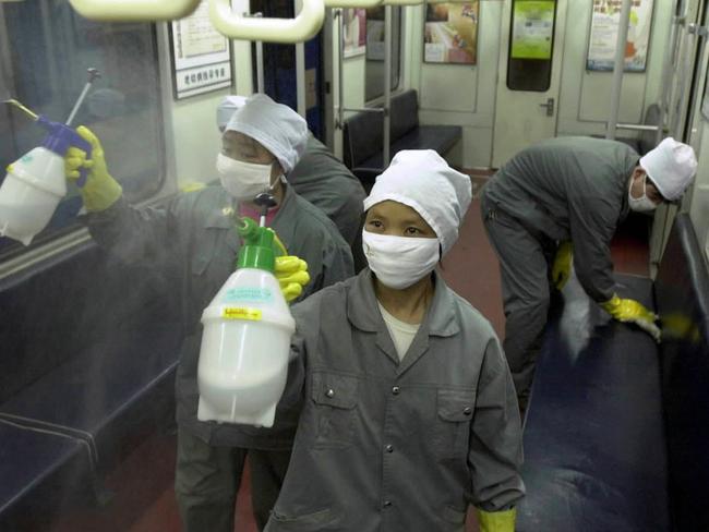 Workers spray disinfectant inside a train car in Beijing during the SARS crisis, April 2003. Picture: AP Photo/Xinhua, Li Wen