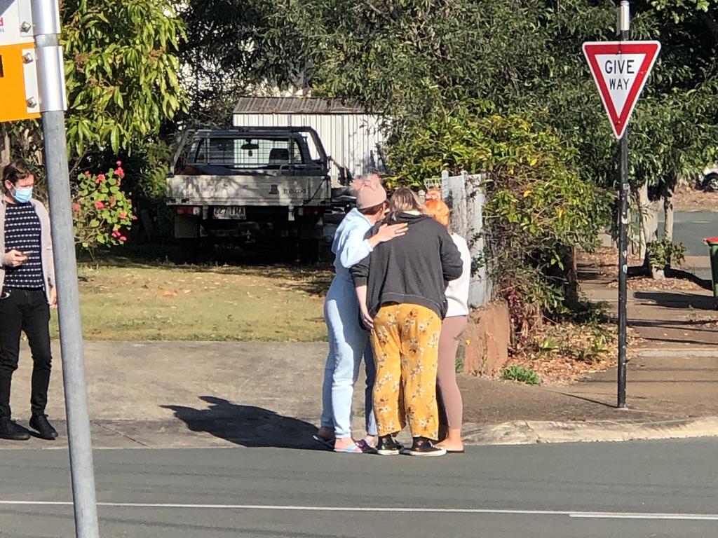 Small business owners stand along Loraine Street, embracing each other.