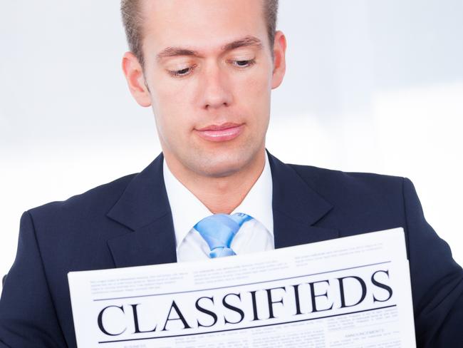 CAREERS: Close-up Of Young Businessman Reading Classifieds On Newspaper.