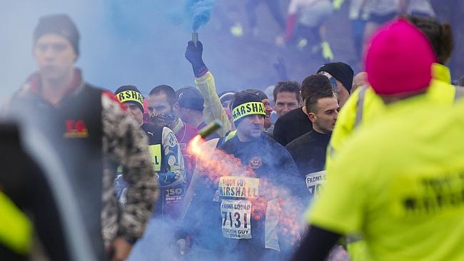 Fireworks and smoke bombs are thrown as competitors wait to start.