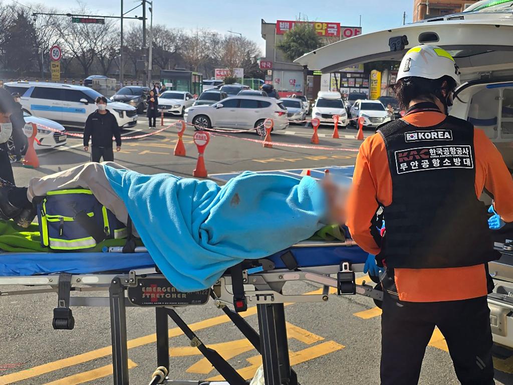 A passenger (face digitally blurred) is transferred from an ambulance to a medical facility following the crash of a Jeju Air Boeing 737-800 series aircraft at Muan International Airport. Picture: AFP