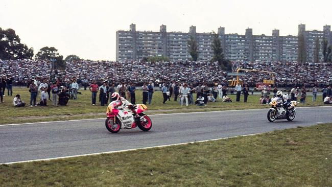 Fans stand trackside as Eddie Lawson and Gardner race past.