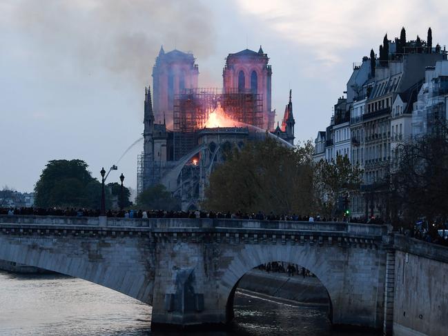 Firefighters douse flames and smoke billowing from the roof at Notre-Dame Cathedral in Paris on April 15, 2019. - A fire broke out at the landmark Notre-Dame Cathedral in central Paris, potentially involving renovation works being carried out at the site, the fire service said. (Photo by Bertrand GUAY / AFP)