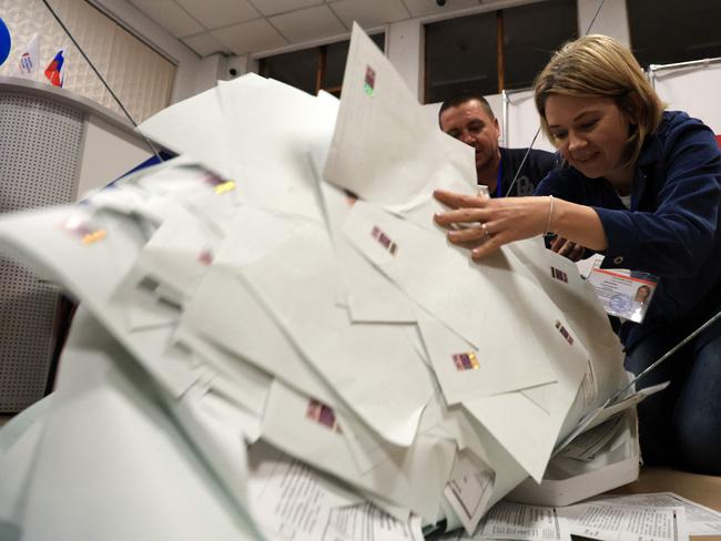 Members of a local electoral commission empty a ballot box at a polling station after polls closed in Russia's presidential election.