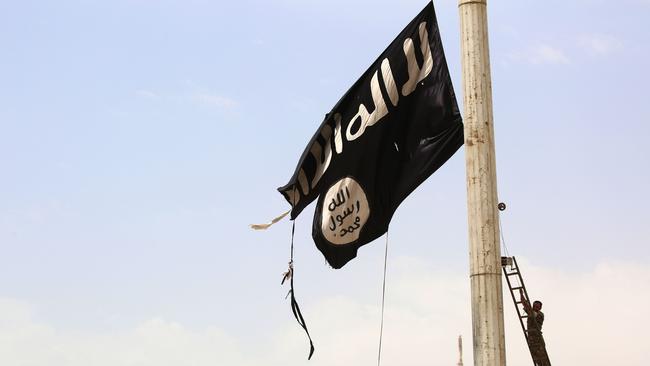 A member of the US-backed Syrian Democratic Forces (SDF) removes an Islamic State group flag in the town of Tabqa. Picture: AFP/Delil Souleiman