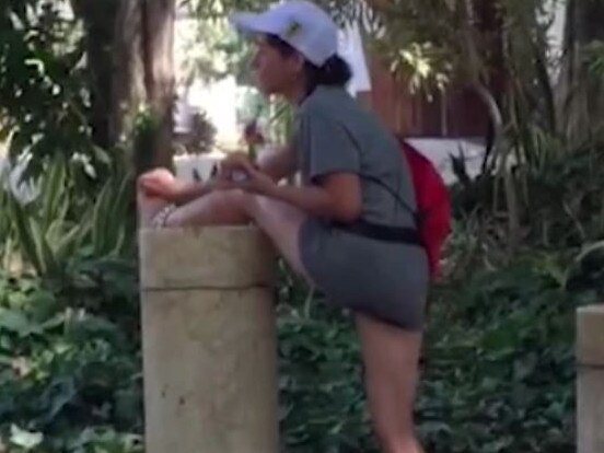 woman shaving her legs in public park