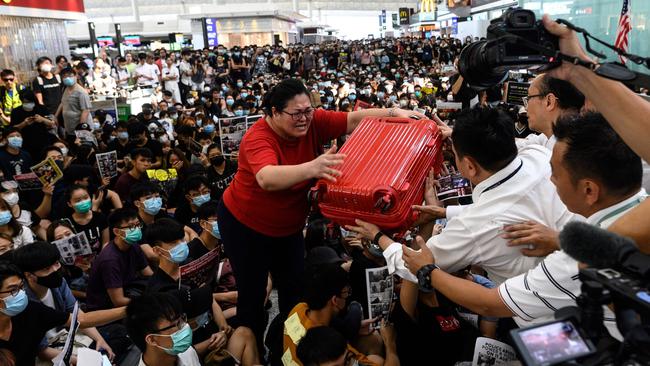 A tourist gives her luggage to security guards as she tries to enter the departures gate during another demonstration. Picture: AFP