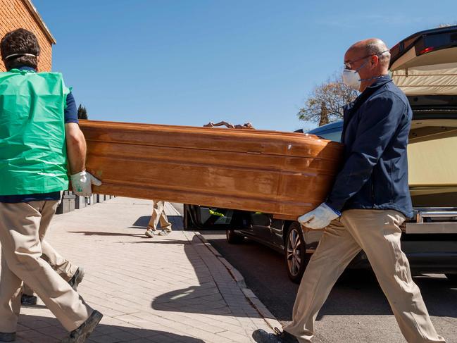 Mortuary employees wearing face masks carry the coffin of a COVID-19 coronavirus victim during a burial at the Fuencarral cemetery in Madrid on March 29, 2020. - Spain confirmed another 838 deaths in 24 hours from coronavirus , a new daily record bringing the total number of deaths to 6,528, according to health ministry figures. The number of confirmed cases in Spain has now reached 78,797 -- after the one-day increase of 9.1 percent -- as the country battles the world's second most deadly outbreak after Italy. (Photo by BALDESCA SAMPER / AFP)