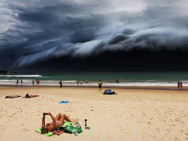 In this image released by World Press Photo titled "Storm Front on Bondi Beach" by photographer Rohan Kelly for the Daily Telegraph which won first prize in the Nature singles category shows a massive cloud tsunami looming over Sydney as a sunbather reads, oblivious to the approaching cloud on Bondi Beach, Sydney, Australia, Nov. 6, 2015. (Rohan Kelly/Daily Telegraph, World Press Photo via AP)