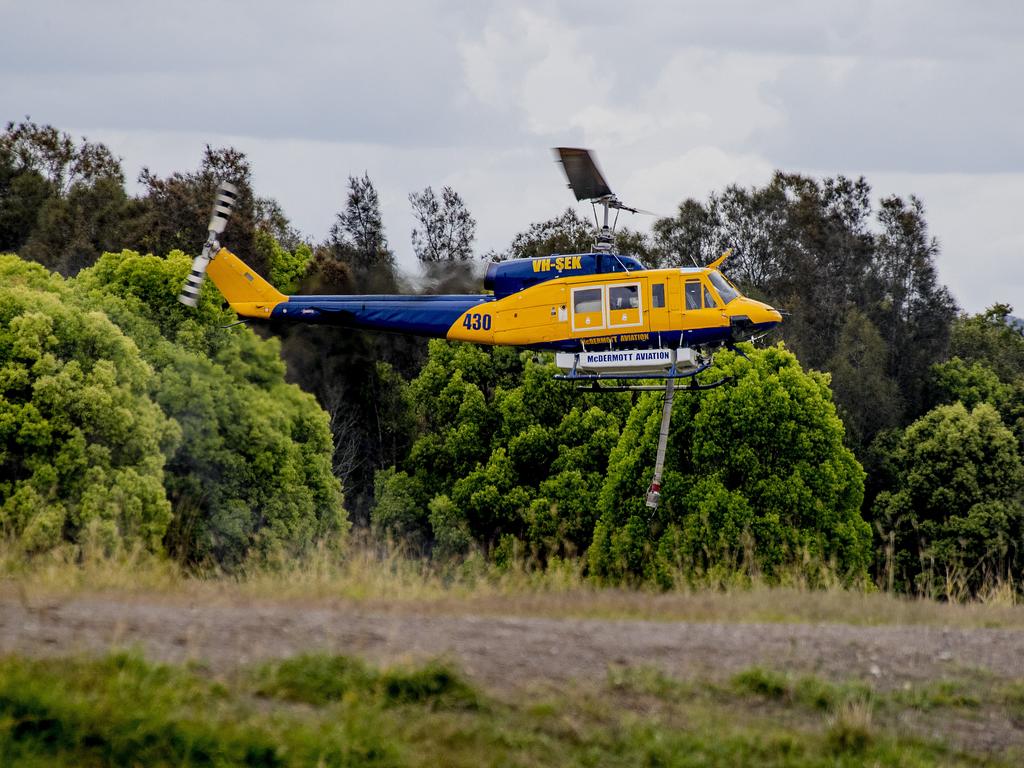 Smoke haze covers the Gold Coast Skyline from a grass fire at Carrara. A firefighting helicopter collects water from Judy Turners property in Carrara . Picture: Jerad Williams