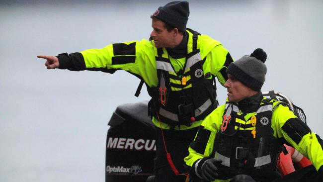 Members of the Alexandria Fire Department look for debris near the crash site of an American Airlines plane along the shoreline of the Potomac River.