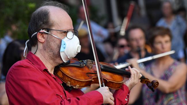 A member of the Opera Australia orchestra performs outside the company office in Sydney on Thursday, urging OA to reconsider its decision to stand down musicians for two weeks and for the federal government to provide emergency financial support to the performing arts sector devastated by the coronavirus pandemic. Picture: Saeed Khan / AFP