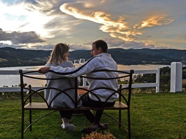 A couple enjoys the peaceful views of the Huon River and Hartz Mountain range from the villa’s grounds. Picture: ZAK SIMMONDS