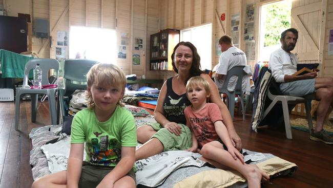 Tracy Walker with Tyler and Roman Archer evacuated to the Machans Beach Community Hall after their house was inundated by flood water. Picture: Peter Carruthers