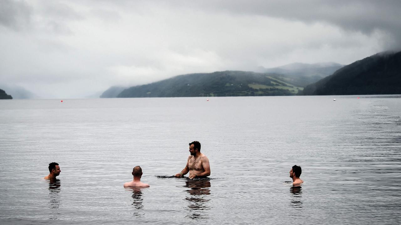 People brave the murky waters of Loch Ness near Dores Beach in Scotland. Picture: Andy Buchanan / AFP