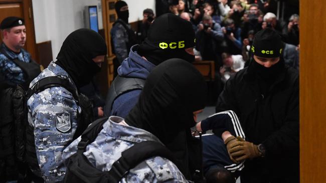 A man suspected of taking part in the attack of a concert hall is escorted by Russian law enforcement officers into a Moscow court. Picture: AFP.