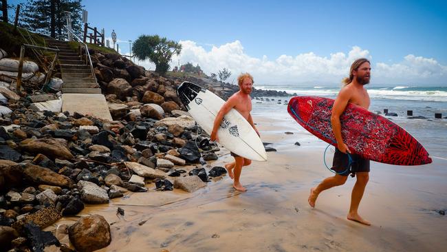 Two surfers negotiate massive beach erosion in the wake of cyclonic conditions at Byron Bay Main Beach on December 15, 2020, after wild weather lashed Australia's Northern New South Wales and South East Queensland with heavy rain, strong winds and king tides. (Photo by Patrick HAMILTON / AFP)