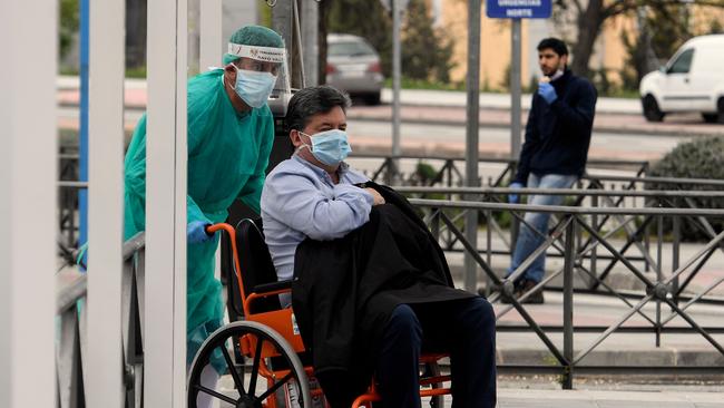 A healthcare worker pushes a man on a wheelchair at the entrance of the 12 Octubre Hospital in Madrid. Picture: AFP