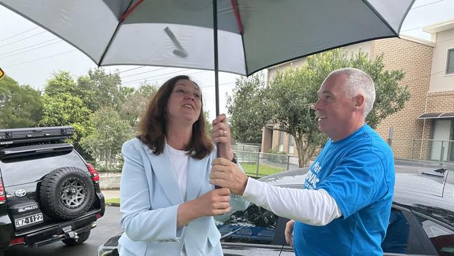 Maria Kovacic’s husband Glenn Gibson helps shelter her from the rain as she arrives at Telopea Public School shortly before polling booths close.