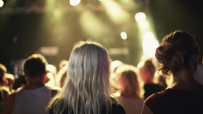 RendezView. Concert. Waiting. (Pic: iStock). Rear view of an audience watching a performance on a festival stage.