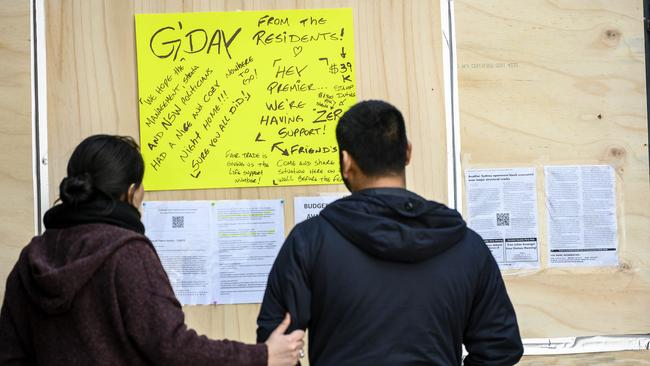 Residents reading billboards posted at entrance to Mascot Towers. Picture: Darren Leigh Roberts