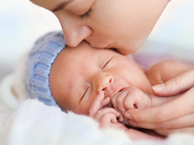 Close up of sleeping newborn and kissing mother