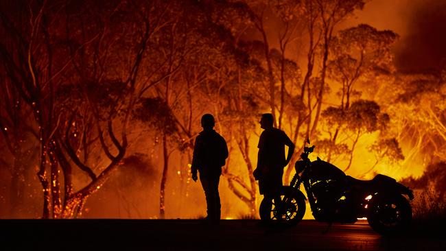 Residents look on as flames burn through bush in Lake Tabourie NSW. Picture: Getty Images