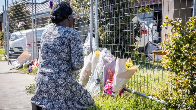 A friend of the family leaves flowers at the scene. Picture: Jake Nowakowski