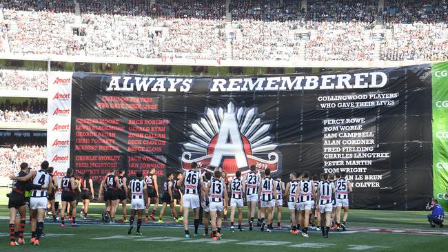 Collingwood and Essendon players run through a joint banner in 2019.