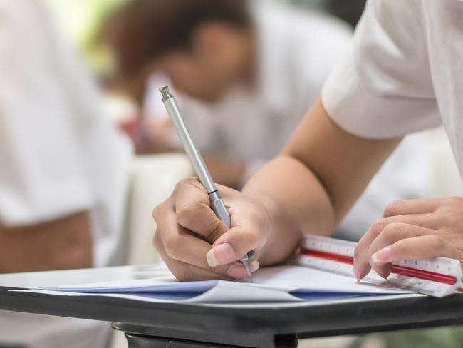 Exam at school with student's taking educational admission test in class, thinking hard, writing answer in university classroom, education and world literacy day concept