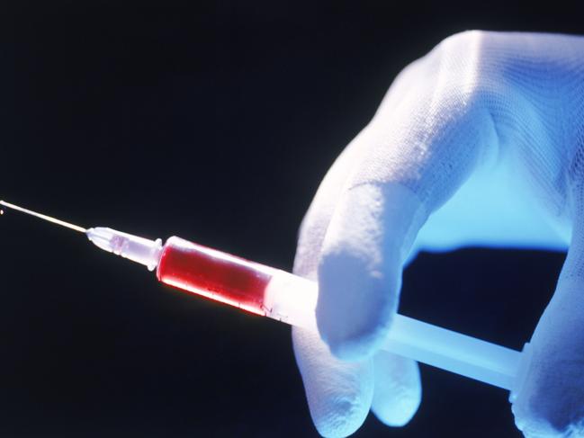 Generic images of medical injection needles from Thinkstock - Gloved hand holding syringe with red liquid inside.