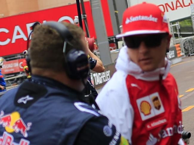 A Red Bull Racing staff member grabs Scuderia Ferrari's Finnish driver Kimi Raikkonen (C) to protect him as Red Bull Racing's German driver Sebastien Vettel (R) leaves the pits of the Monaco street circuit during the second practice session of the Monaco Formula One Grand Prix in Monte Carlo on May 22, 2014. AFP PHOTO / ALEXANDER KLEIN