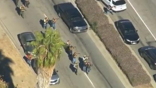 Massacre ... police  walk with their weapons drawn at the scene of the shooting.