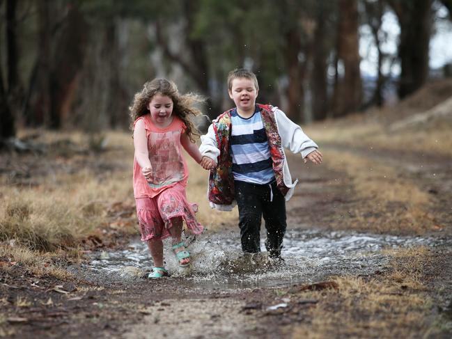 Whyette Peell, 6, and Savannah Richards, 5, welcome the rain on the family farm outside of Tenterfield. Picture: Peter Lorimer