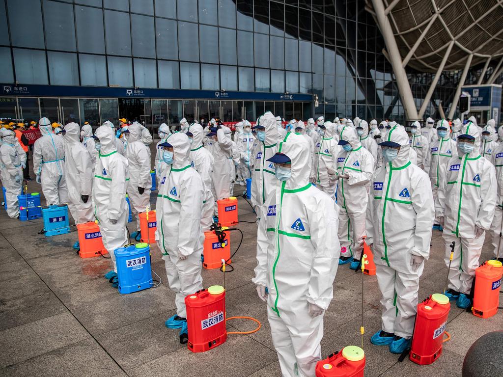 Staff members line up at attention as they prepare to spray disinfectant at Wuhan Railway Station in Wuhan. Picture: STR / AFP